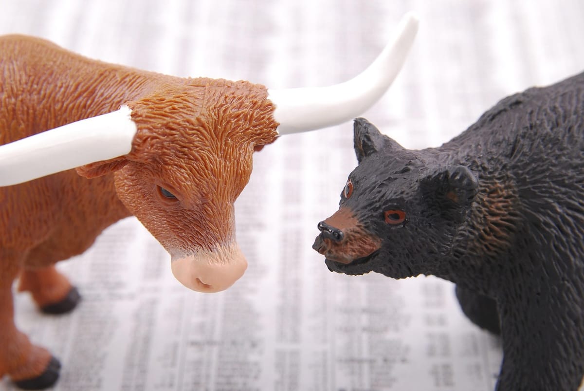 Bull and bear figurines on a stock market chart representing financial markets