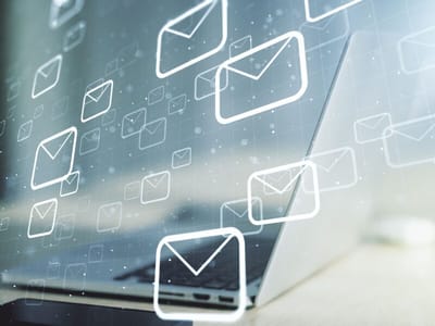 Laptop screen overlaid with floating email envelope icons, investment newsletters
