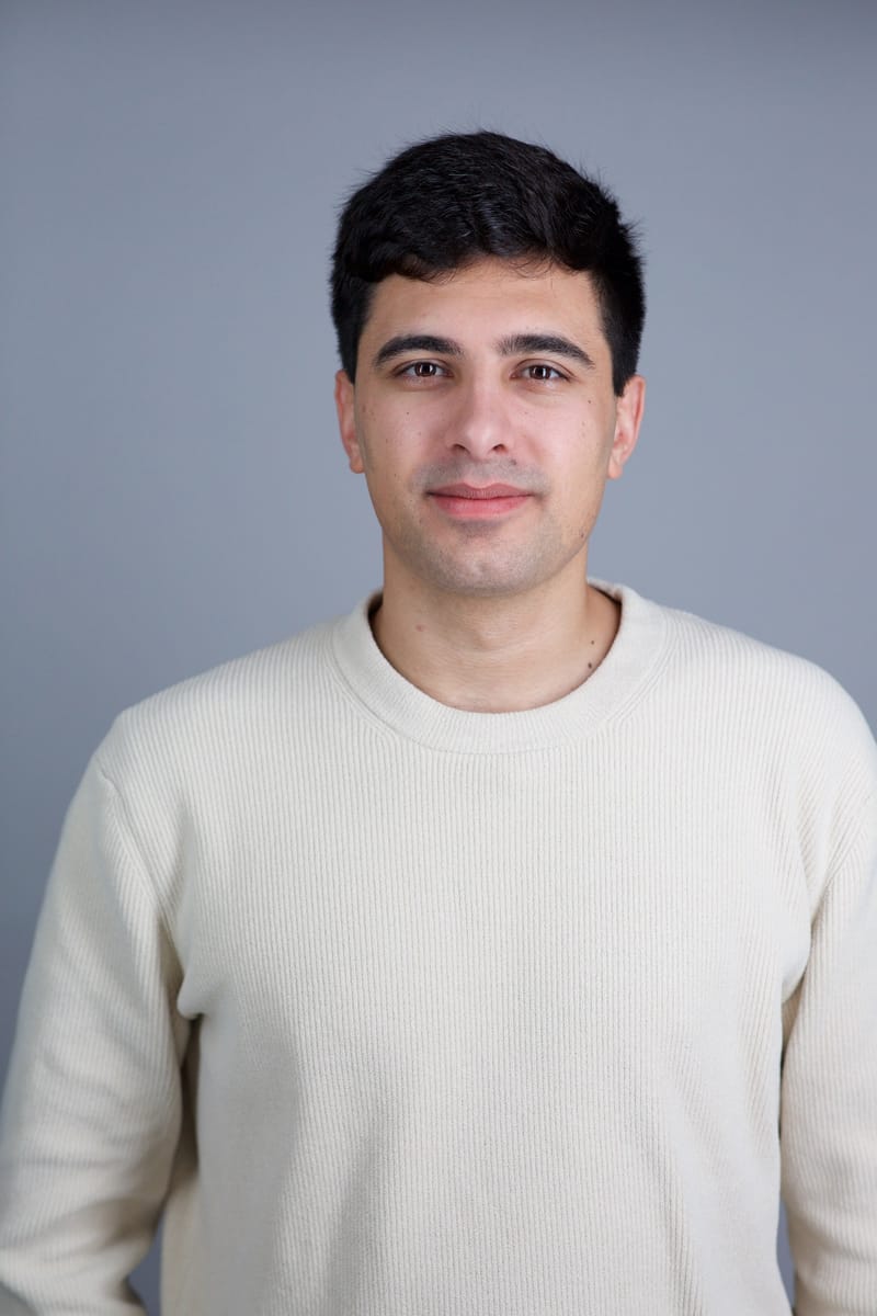 Edwin Dorsey, founder of The Bear Cave, vertical headshot in a cream sweater on a gray studio background