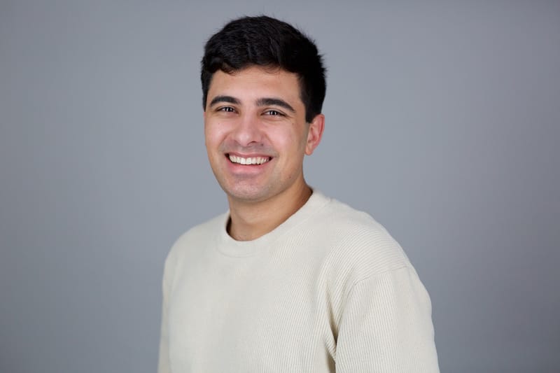 Edwin Dorsey, founder of The Bear Cave newsletter, smiling in a cream sweater against a gray studio background